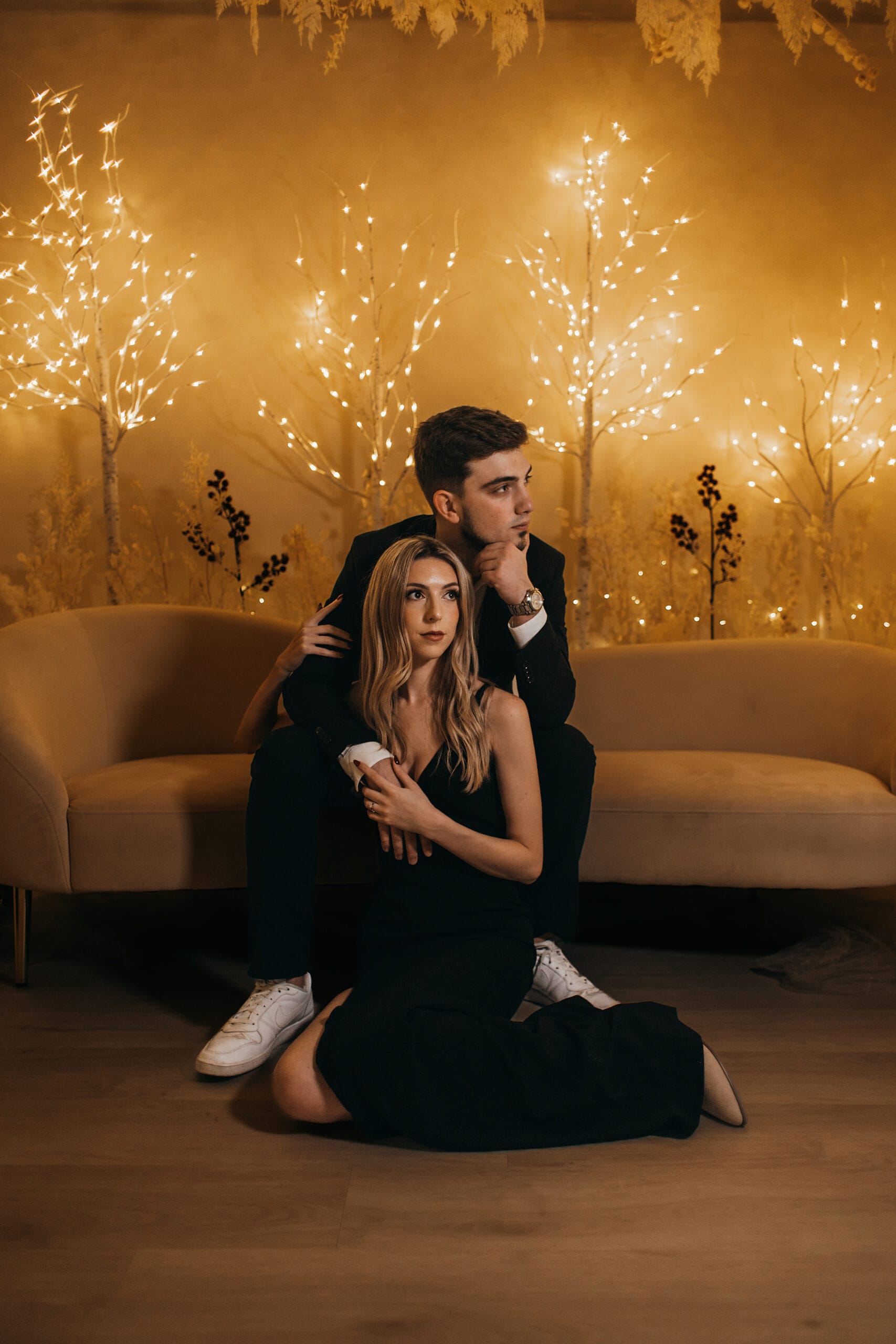 Winter engagement photoshoot of a couple in an elegant indoor setting with warm lights