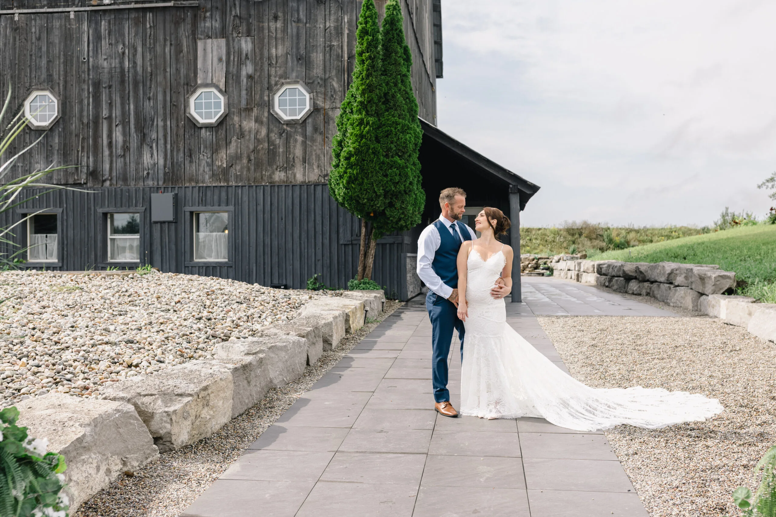 Bride and groom walking beside the barn at The Ranch Wedding and Events